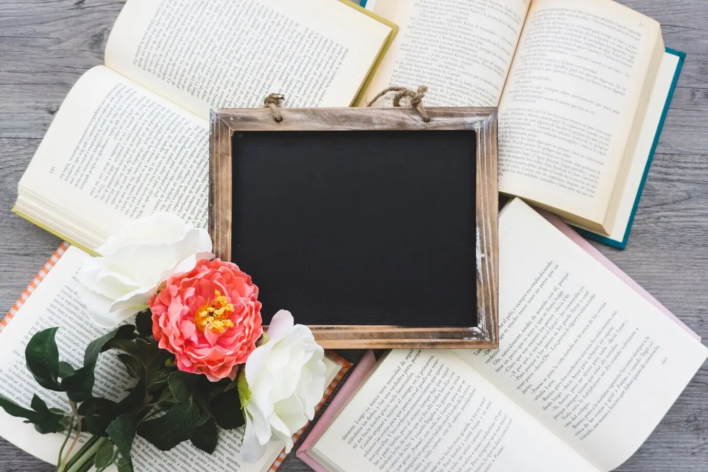 Komposition mit einer dekorativen Schiefertafel auf aufgeschlagenen Büchern.